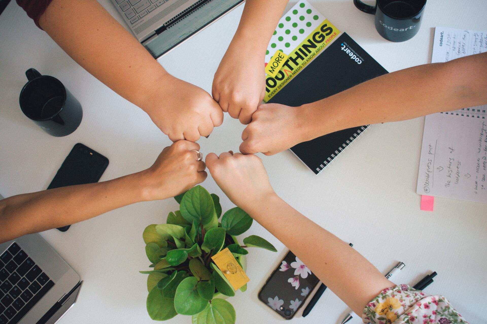 A diverse team joining hands around a table